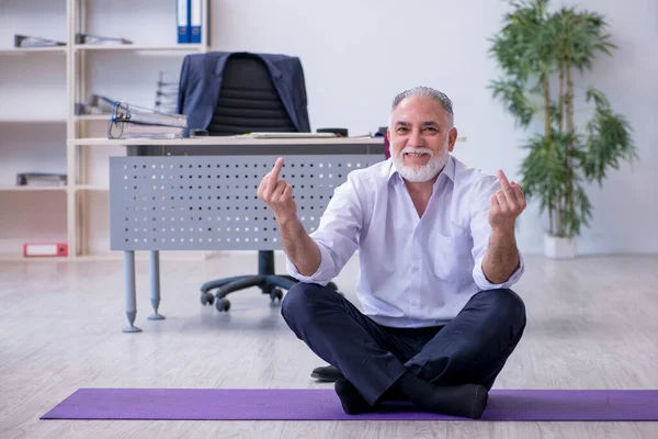 Employé masculin âgé faisant des exercices physiques pendant la pause — Photo