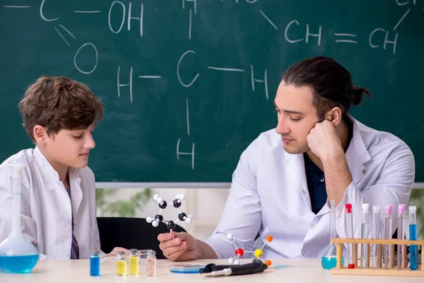 Young chemistry teacher and schoolboy in the classroom — Stock Photo, Image