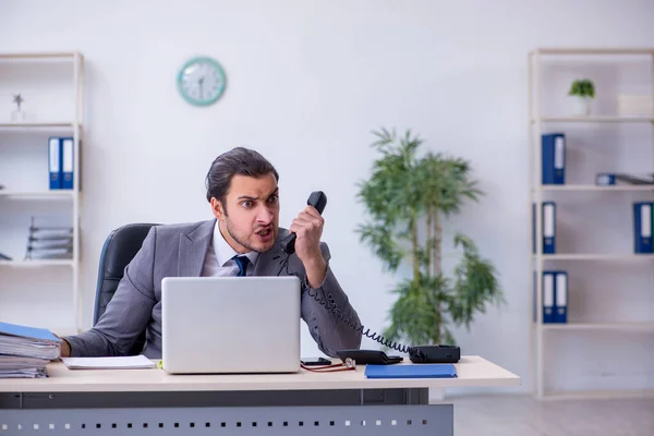 Junge männliche Angestellte unzufrieden mit exzessiver Arbeit im Büro — Stockfoto