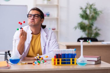Genç erkek kimyager sınıfta moleküler model üzerinde çalışıyor.