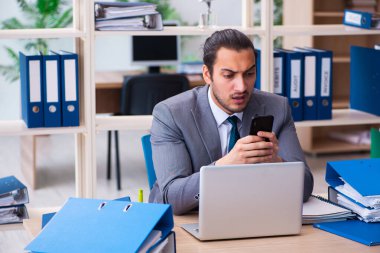 Genç bir erkek çalışan ve ofiste çok fazla iş var.