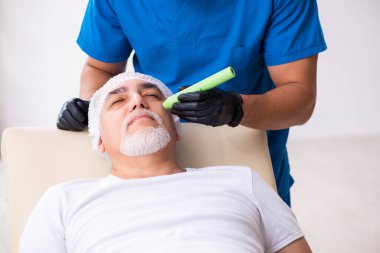 Yaşlı adam estetik ameliyat için erkek doktoru ziyaret ediyor.