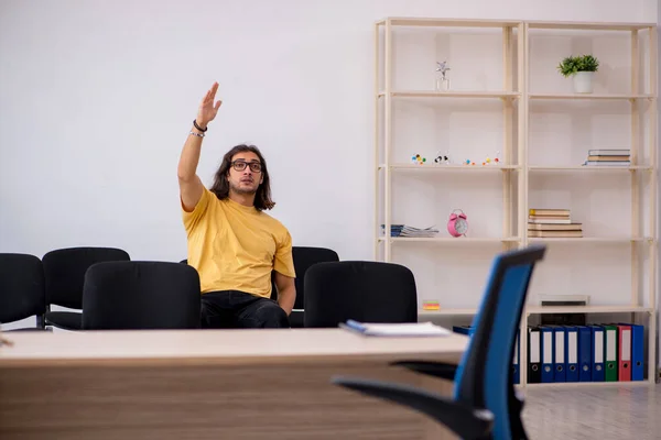 Jonge mannelijke student wachtend op leraar in de klas — Stockfoto