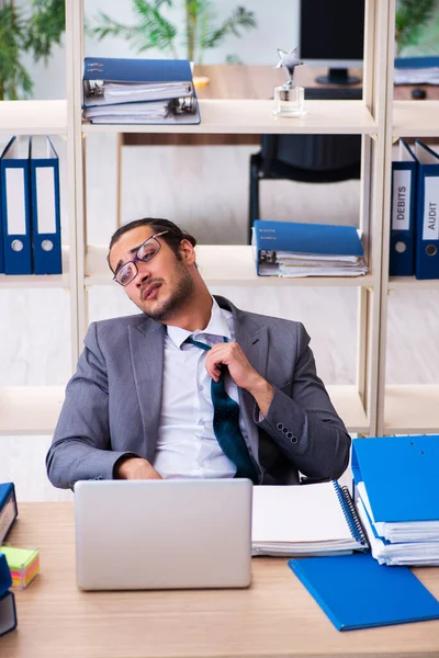 Jovem funcionário masculino e muito trabalho no escritório — Fotografia de Stock