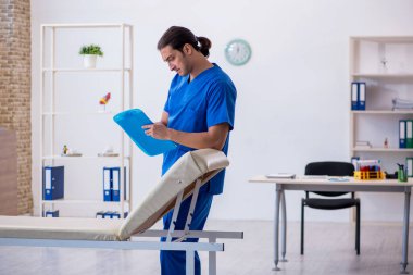 Genç erkek doktor hastanede not alıyor.