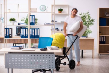 İş yerinde yeni doğan bebeğe bakan genç bir erkek işçi.