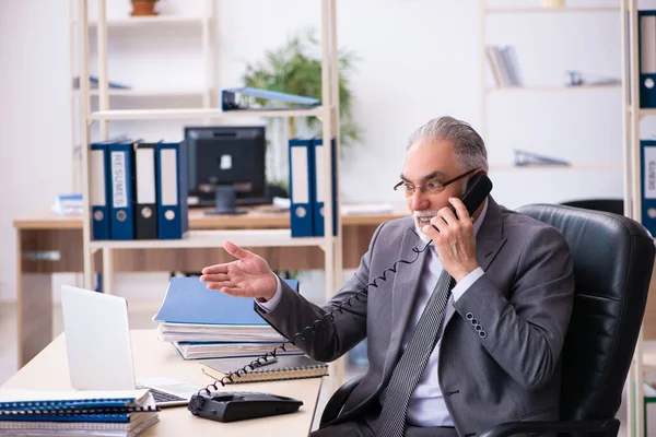 Starý muž zaměstnanec pomocí telefonu v kanceláři — Stock fotografie