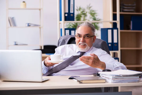 Oude mannelijke werknemer die koffie drinkt op kantoor — Stockfoto