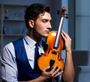 Genç müzisyen evde keman çalıyor.