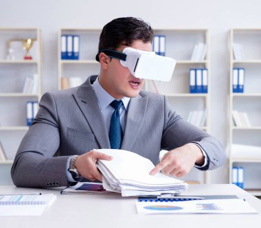 Ofiste sanal gerçeklik gözlüklü bir iş adamı var.