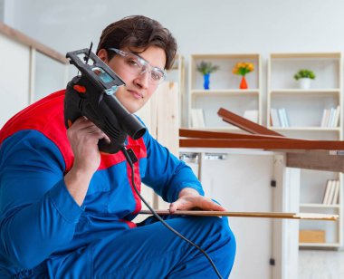 Genç marangoz ahşap kalaslarla çalışıyor.