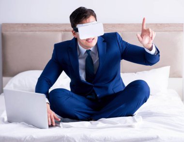 Yatak odasında sanal gerçeklik kulaklığı takan bir iş adamı.