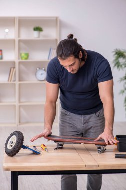 Kaykay tamir eden genç bir erkek tamirci.