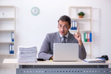 Ofisteki aşırı işten memnun olmayan genç bir erkek işçi.