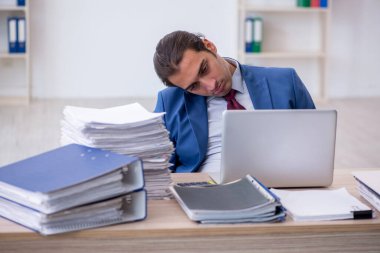 Ofisteki aşırı işten memnun olmayan genç bir erkek işçi.