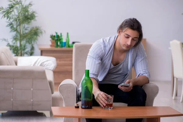 Genç erkek alkolik partiden sonra televizyon izliyor. — Stok fotoğraf