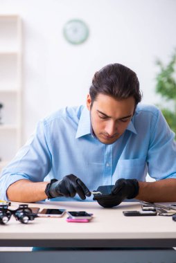 Cep telefonunu tamir eden genç bir teknisyen.