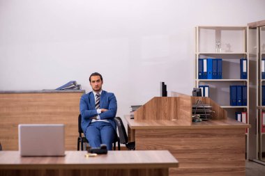 Genç erkek çalışan işyerinde oturuyor.