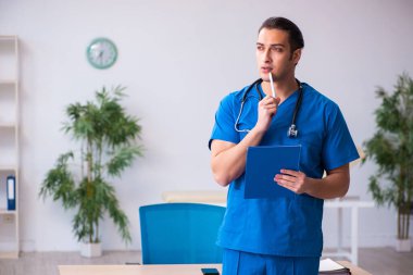 Klinikte çalışan genç erkek doktor.