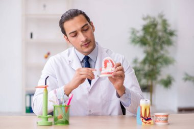 Genç erkek doktor stomatolojist klinikte çalışıyor.