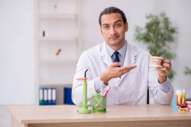 Genç erkek doktor stomatolojist klinikte çalışıyor.