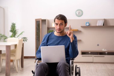 Evde acı çeken tekerlekli sandalyedeki genç adam.