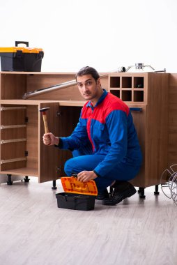 Genç yakışıklı erkek marangoz içeride çalışıyor.