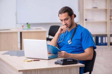 Genç erkek doktor klinikte not alıyor.