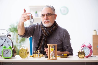 Atölyede çalışan yaşlı bir erkek saatçi.