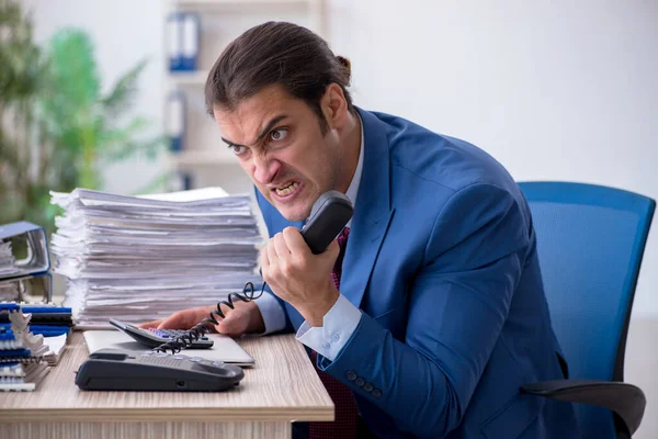 Junge männliche Angestellte unzufrieden mit exzessiver Arbeit im Büro — Stockfoto