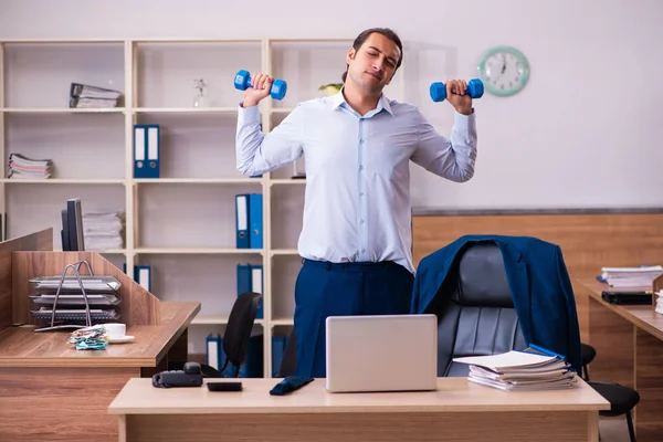 Jonge mannelijke werknemer doet fysieke oefeningen op de werkplek — Stockfoto