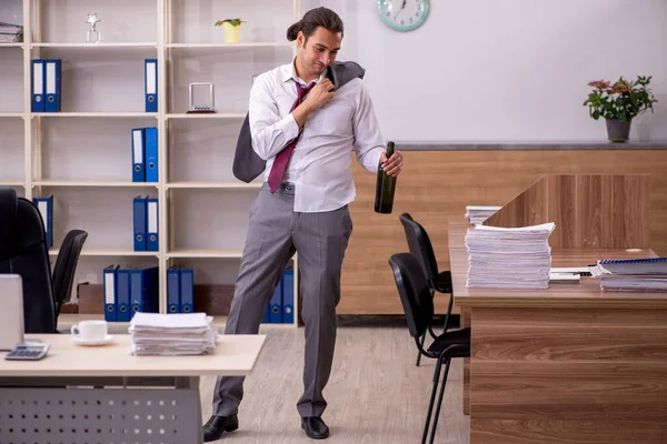 Ung manlig anställd dricker alkohol på kontoret — Stockfoto