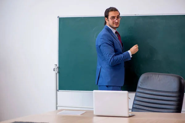 Junger männlicher Lehrer im Anzug vor grünem Brett — Stockfoto