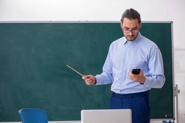 Jonge mannelijke leraar in de klas voor het groene bord — Stockfoto