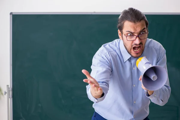 Jovem professor na sala de aula segurando megafone — Fotografia de Stock