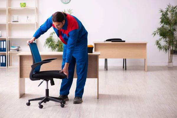 Young male contractor repairing furniture in the office