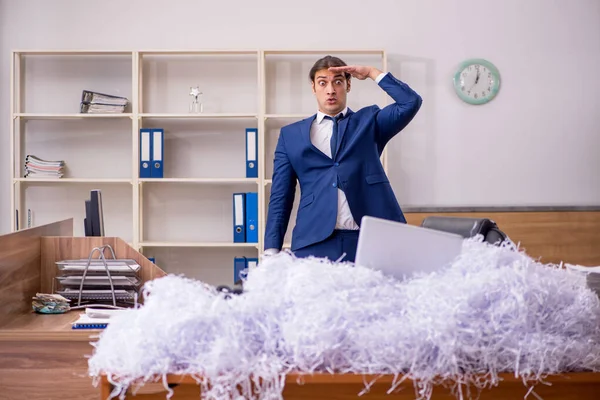 Молодой работник и куча разрезанных бумаг в офисе — стоковое фото