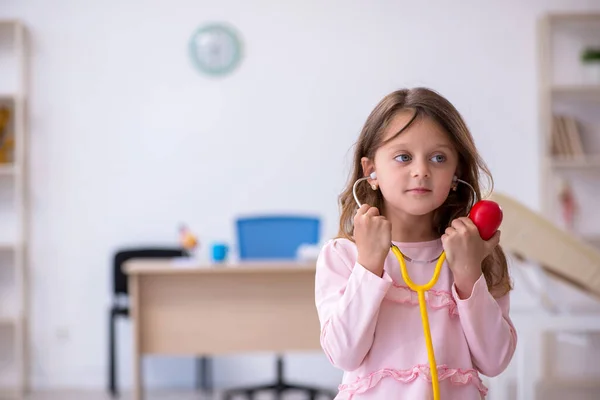 Petite fille tenant stéthoscope attendant un médecin à la clinique — Photo