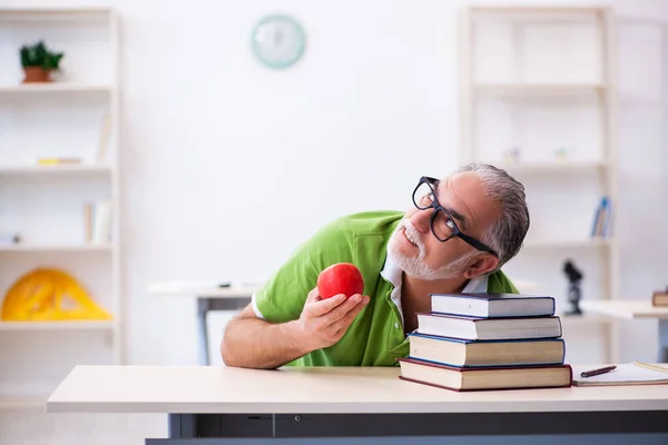 Velho estudante do sexo masculino comer maçã durante a preparação do exame — Fotografia de Stock