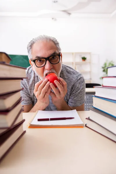 Oude mannelijke student eet appel tijdens de voorbereiding van het examen — Stockfoto