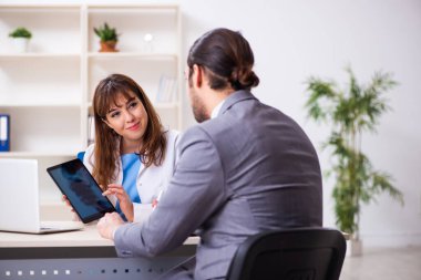 Genç bayan doktor ve hasta iş adamı ofiste.