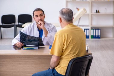 Yaşlı hasta, genç erkek doktor radyolojisti ziyaret ediyor.