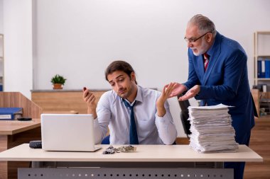 Genç erkek çalışan ve yaşlı patron iş yerinde kağıtları yakıyor.