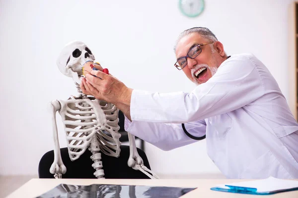診療所での古い男性医師の心臓専門医と骨格患者 — ストック写真