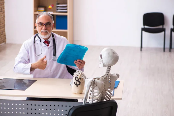 Oude mannelijke arts cardioloog en skelet patiënt in dure m — Stockfoto
