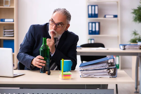 Gammal manlig anställd dricker alkohol på kontoret — Stockfoto