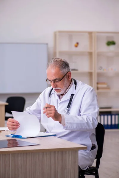 Old male doctor working in the clinic — Stock Photo, Image