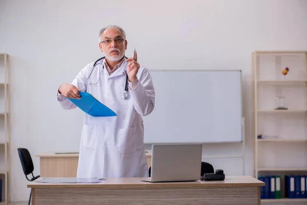 Oude mannelijke arts werkzaam in de kliniek — Stockfoto