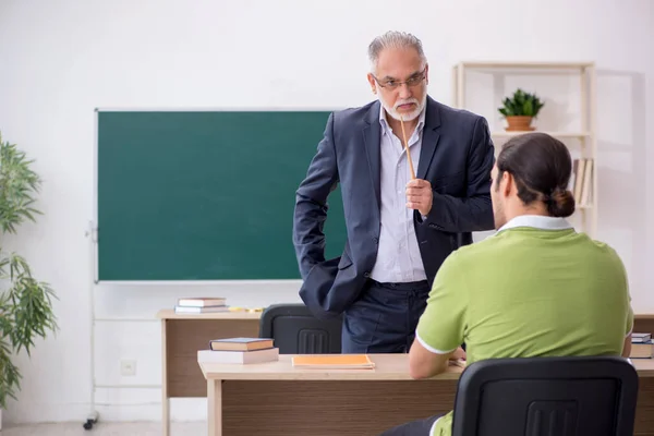 Leeftijd leraar en jonge mannelijke student in de klas — Stockfoto