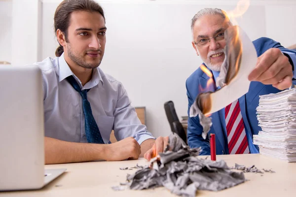 Joven empleado masculino y viejo jefe quemando papeles en el lugar de trabajo — Foto de Stock